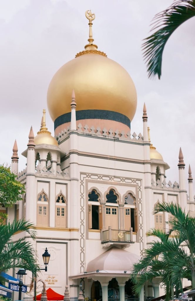 sultan-mosque-in-singapore-with-golden-dome-29480519 Elegant view of Sultan Mosques golden dome in Singapore, surrounded by palm trees.
